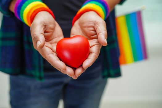 Asian woman holding red hert with rainbow flag, LGBT symbol rights and gender equality, LGBT Pride Month in June, LGBTQ, LGBTI, LGBTQA, LGBTQIA