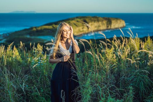 Young beautiful woman in autumn landscape with dry flowers, wheat spikes. Fashion autumn, winter. Sunny autumn, fashion photo.