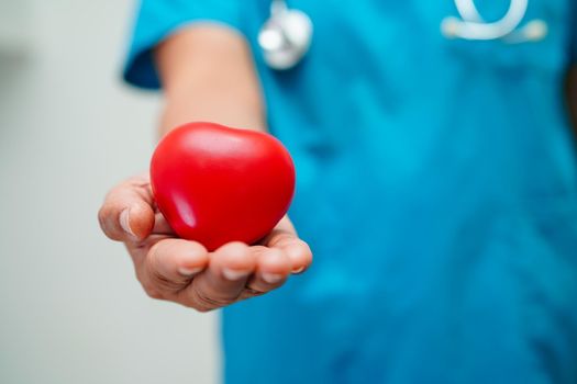 Asian woman doctor holding red heart for health in hospital.
