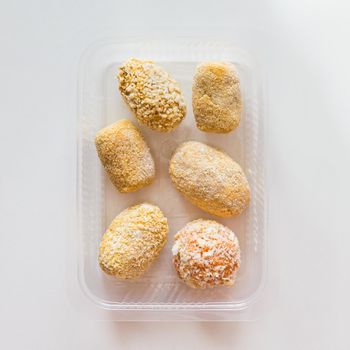 Assortment of raw frozen croquettes in transparent tray. Mediterranean and spanish cuisine. Preserved food for sale. Top view.