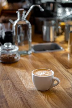 Heart shape foam drawed on cappuccino on wooden table at vintage cafe.