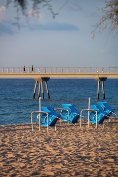 Closed beach cafe with blue chairs. Pontoon and sea at the background. Badalona, Barcelona, Catalonia, Spain