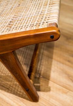 Detail of back part of modern wicker chair standing in a living room with laminate. Interior wooden furniture