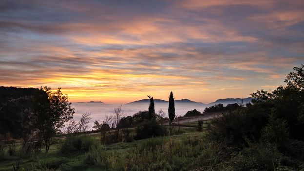 Yellow dawn with blue sky above the clouds. View from high point. Very early morning with fog and colorful clouds.