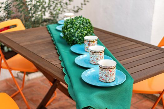 Cozy summer backyard with outdoor table and chairs. Patio with tea table with tea cups and blue plates. Village backyard.