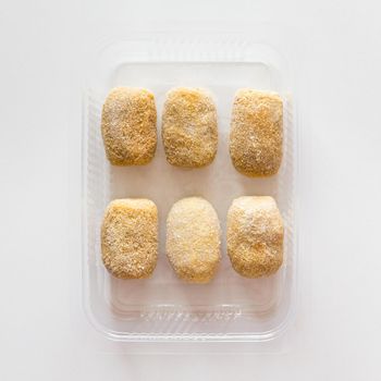 Homemade frozen croquettes in transparent tray. Mediterranean and spanish cuisine. Preserved food for sale. Top view.