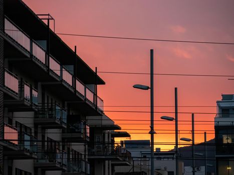 Orange pink red sunset at a city with building and lanterns silhouettes