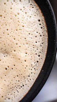 Close-up of pancake on iron frying pan. Cooking delicious crepes at home. Top view.