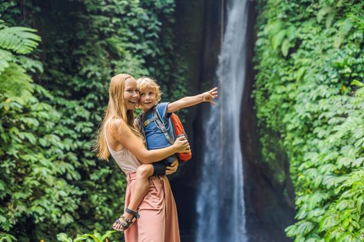 Mom and son travelers on the background of Leke Leke waterfall in Bali island Indonesia. Traveling with children concept.