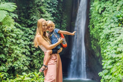 Mom and son travelers on the background of Leke Leke waterfall in Bali island Indonesia. Traveling with children concept.