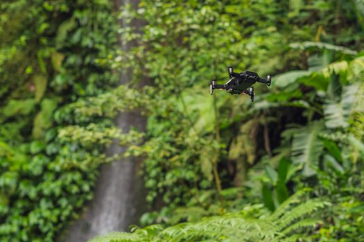 Little quadcopter flying around waterfall Leke Leke Bali island Indonesia.