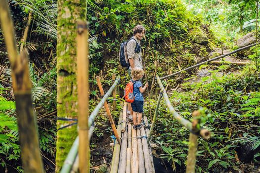 Father and son travelers on the suspension bridge in Bali. Traveling with children concept..