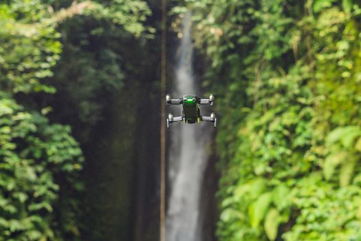 Little quadcopter flying around waterfall Leke Leke Bali island Indonesia.