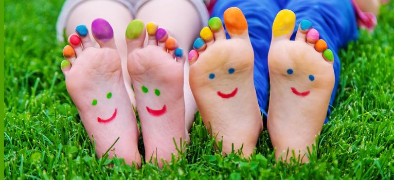 Children's feet with a pattern of paints smile on the green grass. Selective focus.child