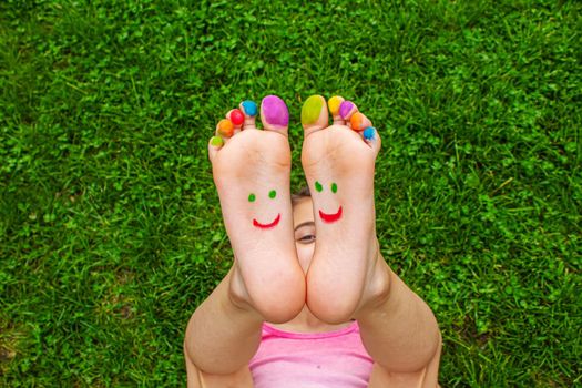 Children's feet with a pattern of paints smile on the green grass. Selective focus.child