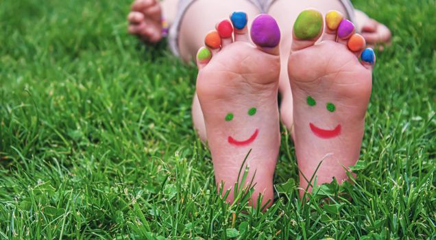 Children's feet with a pattern of paints smile on the green grass. Selective focus.child