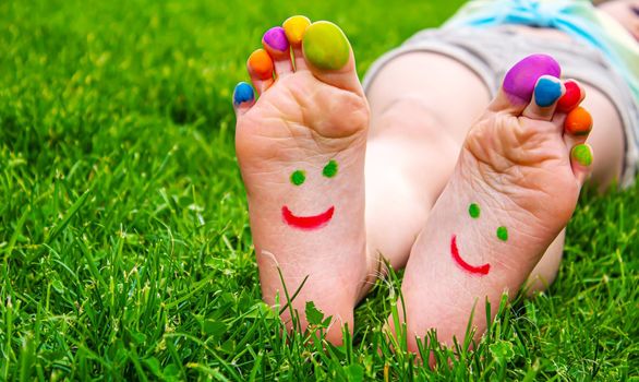 Children's feet with a pattern of paints smile on the green grass. Selective focus.child