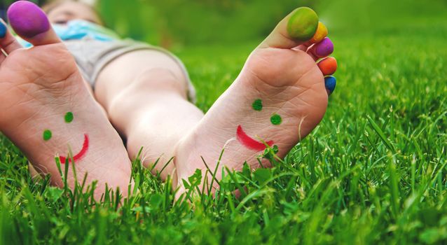 Children's feet with a pattern of paints smile on the green grass. Selective focus.child