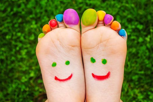 Children's feet with a pattern of paints smile on the green grass. Selective focus.child
