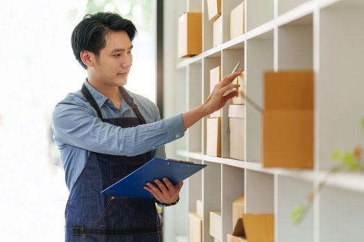 A portrait of Asian man, e-commerce employee freelance with parcel box for deliver to customer. Online marketing packing box delivery concept