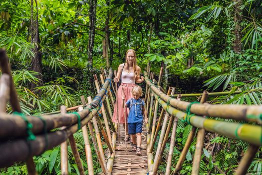 Mom and son travelers on the suspension bridge in Bali. Traveling with children concept..