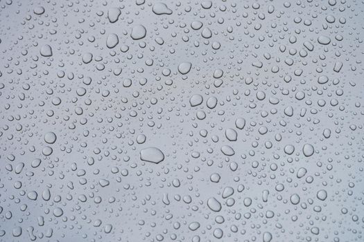 Closeup of raindrops on gray window glass texture background. . Rainy weather concept and natural condensation wallpaper.