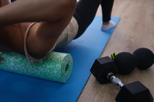 Woman does exercises lying on roller and balancing. Home exercises and strengthens back muscles