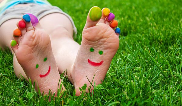 Children's feet with a pattern of paints smile on the green grass. Selective focus.child