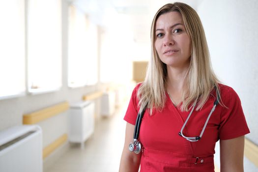 Young woman doctor with stethoscope in clinic. Medical insurance and assistance concept