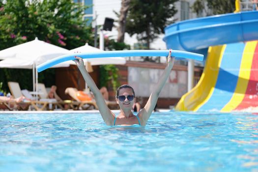 Woman is relaxing in pool and doing aqua aerobics. Happy woman enjoying workout in pool.