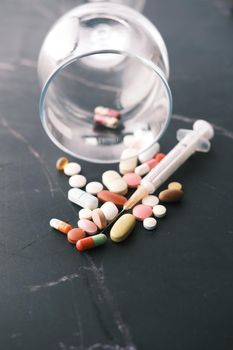 syringe and pills on dark background, close up.