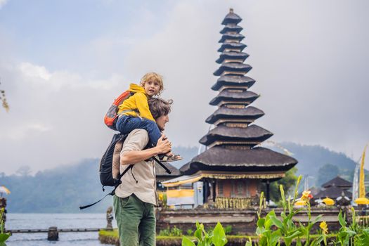 Dad and son in the background of Pura Ulun Danu Bratan, Bali. Hindu temple surrounded by flowers on Bratan lake, Bali. Major Shivaite water temple in Bali, Indonesia. Hindu temple. Traveling with children concept.