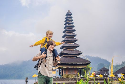 Dad and son in the background of Pura Ulun Danu Bratan, Bali. Hindu temple surrounded by flowers on Bratan lake, Bali. Major Shivaite water temple in Bali, Indonesia. Hindu temple. Traveling with children concept.