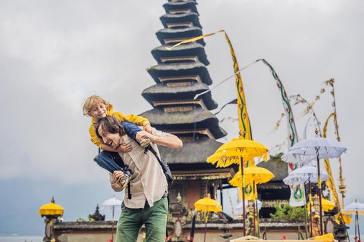 Dad and son in the background of Pura Ulun Danu Bratan, Bali. Hindu temple surrounded by flowers on Bratan lake, Bali. Major Shivaite water temple in Bali, Indonesia. Hindu temple. Traveling with children concept.