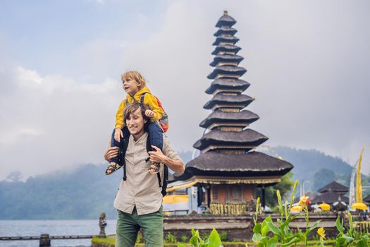 Dad and son in the background of Pura Ulun Danu Bratan, Bali. Hindu temple surrounded by flowers on Bratan lake, Bali. Major Shivaite water temple in Bali, Indonesia. Hindu temple. Traveling with children concept.