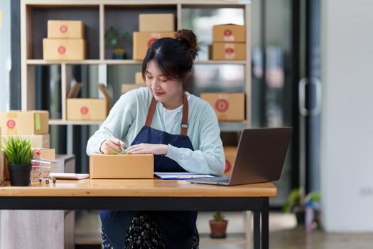 A portrait of Asian woman, e-commerce employee freelance with parcel box for deliver to customer. Online marketing packing box delivery concept