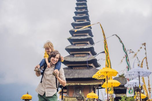 Dad and son in the background of Pura Ulun Danu Bratan, Bali. Hindu temple surrounded by flowers on Bratan lake, Bali. Major Shivaite water temple in Bali, Indonesia. Hindu temple. Traveling with children concept.