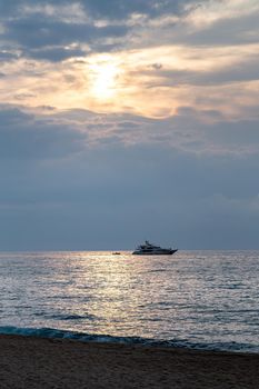 Yacht sailing against sunrise. Holiday lifestyle vertical shot with skyline sailboat. Yachting tourism - maritime walk. Romantic trip on luxury yacht during the sea sunset or surise.