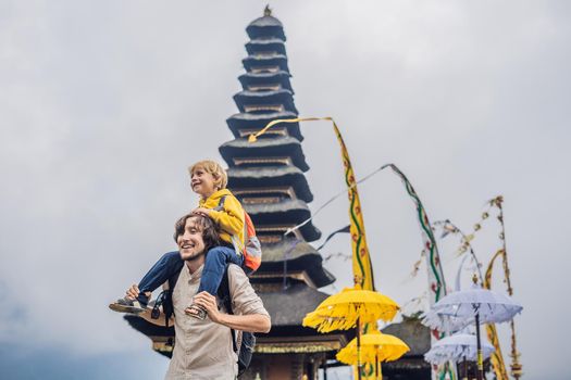 Dad and son in the background of Pura Ulun Danu Bratan, Bali. Hindu temple surrounded by flowers on Bratan lake, Bali. Major Shivaite water temple in Bali, Indonesia. Hindu temple. Traveling with children concept.