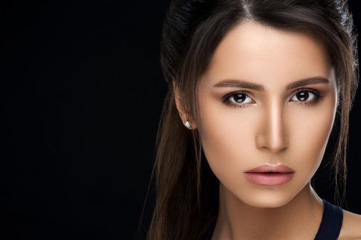 Close up of gorgeous and seductive woman with perfect bronze clean skin, plumps lips, confident looking at camera. Young brunette girl after procedure and makeup in beauty salon. Concept of beauty.