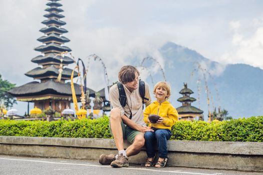 Dad and son in the background of Pura Ulun Danu Bratan, Bali. Hindu temple surrounded by flowers on Bratan lake, Bali. Major Shivaite water temple in Bali, Indonesia. Hindu temple. Traveling with children concept.