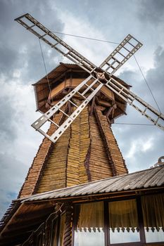 Windmill. Big wooden mill on gray cloudy dramatic sky background.