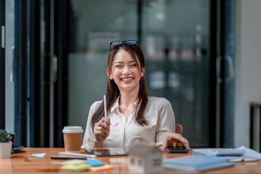 Portrait of happy young asian girl working at a coffee shop with a digital tablet and pen stylus. Real estate concept.