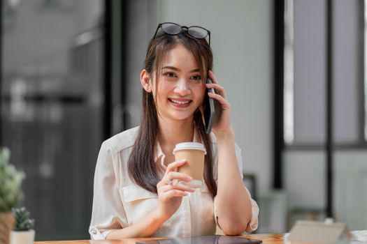 Portrait of young asian businesswoman beautiful charming smiling and talking on the mobile phone in the office.