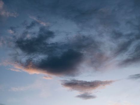 The dramatic sky. A black cloud in the sky. Cloud with a full range of colors from black to light tones of red and yellow on the eve of the day.

