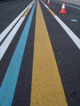Various lines painted on asphalt. Yellow, blue, white. Part of a training ground for drivers.