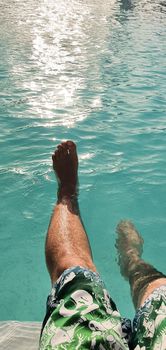 man relaxing in the pool with his legs in the water