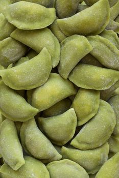 Frozen vegetable dumplings texture in the market fridge as a background. Dough colored green with spinach juice.