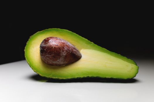 background. cut avocado in half, with a bone inside, lies on the table. view from above.