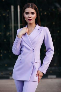 Portrait of a business woman with a determined look. The girl is dressed in a strict pale purple suit. Isolated on a blurred urban background. Concept of business lady. Close-up.